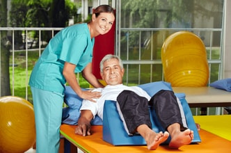 Man smiling with nurse. He is laying on a therapeutic table.